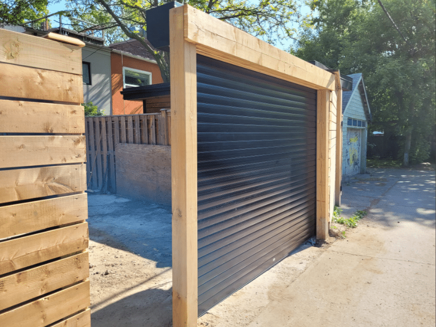 Black aluminum roll-up garage door installed on a narrow laneway in Toronto