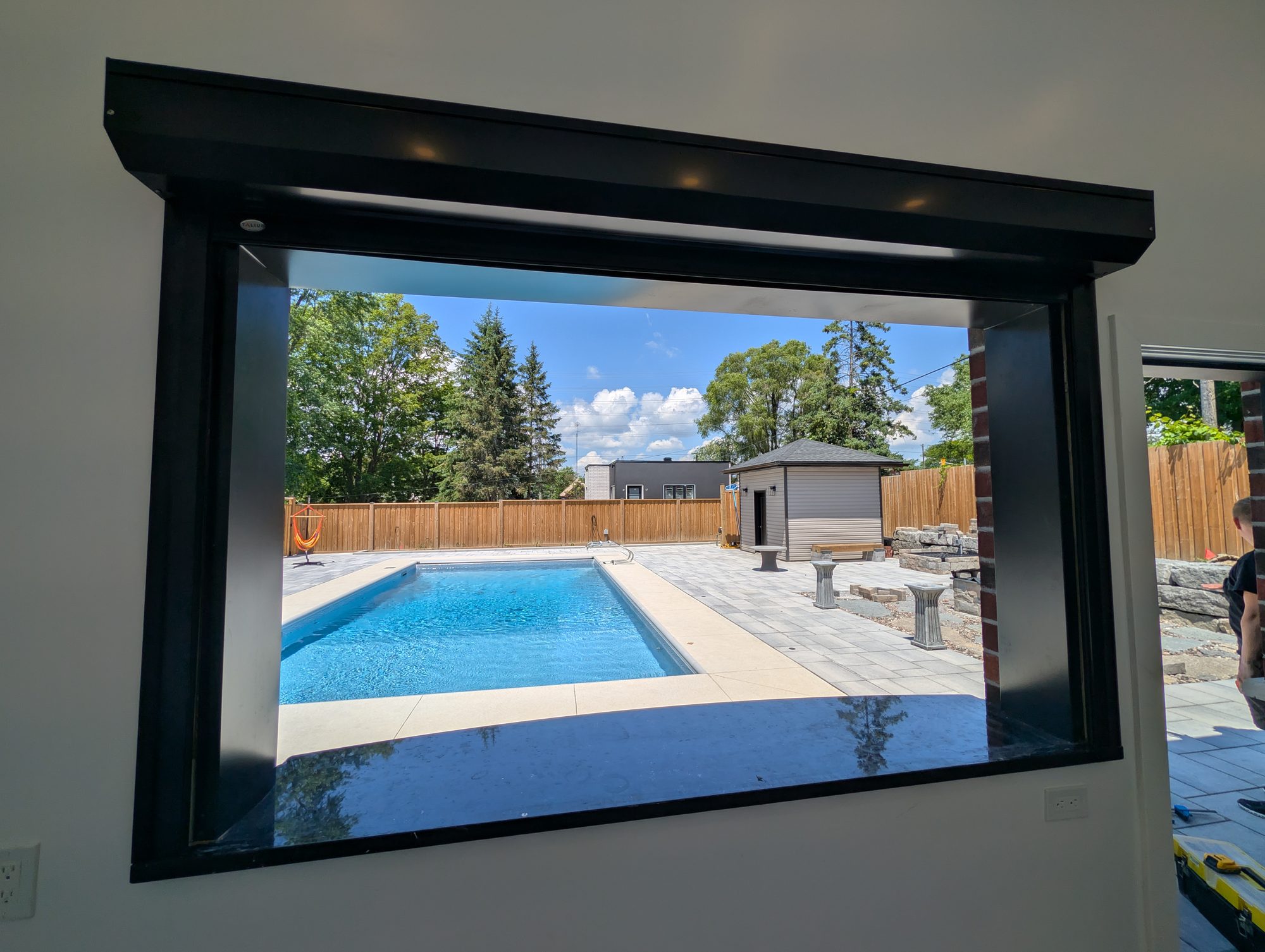 Pool house servery opening with the roll shutter retracted into its headbox, overlooking a backyard pool