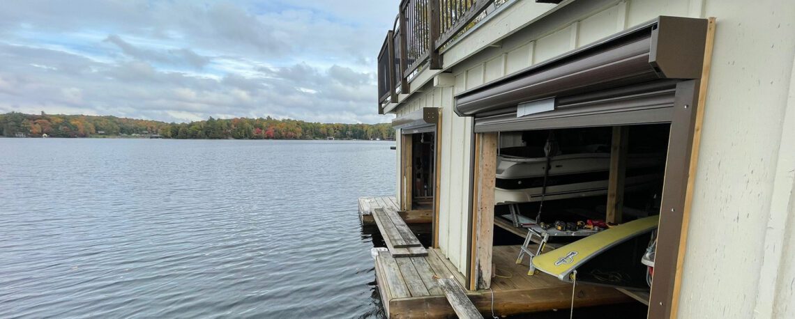 Waterfront boathouse with dual roll-up garage doors on the water