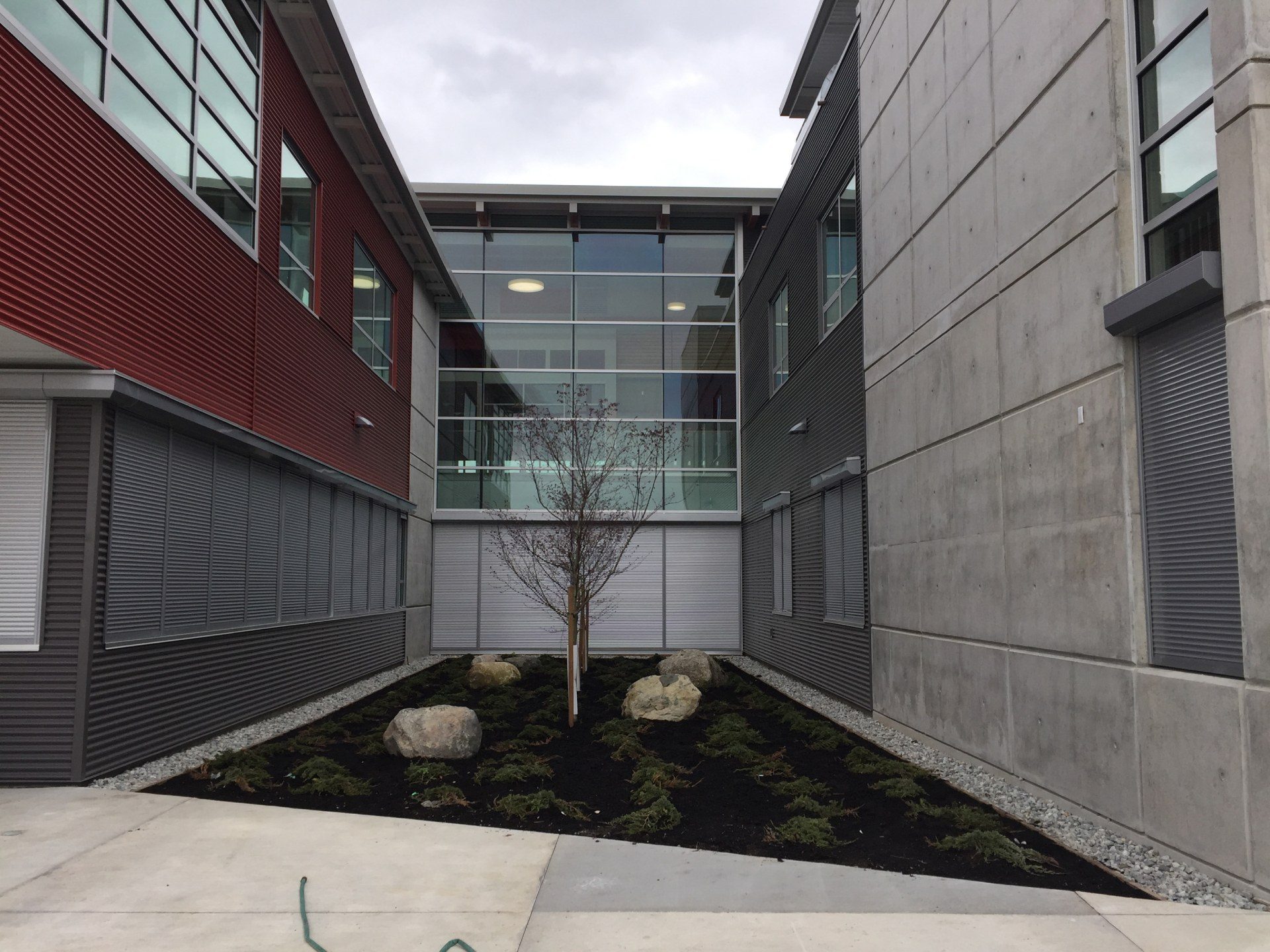 Grey roll shutters closed on ground-floor windows along both sides of a school courtyard