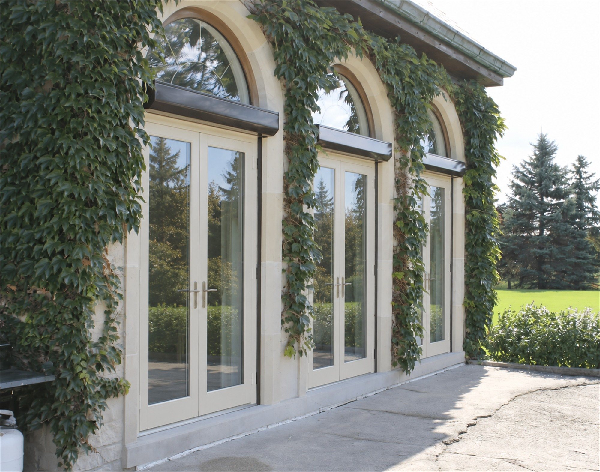 Illustration of cream roll shutters raised above three arched French doors on an ivy-covered stone house