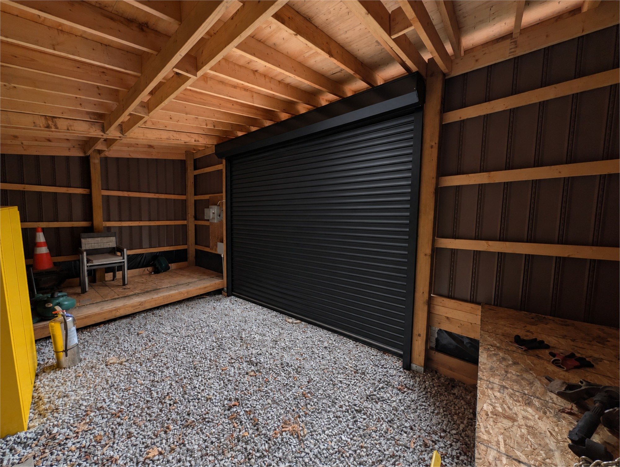Illustration of the same black roll-up door closed, seen from inside the shed