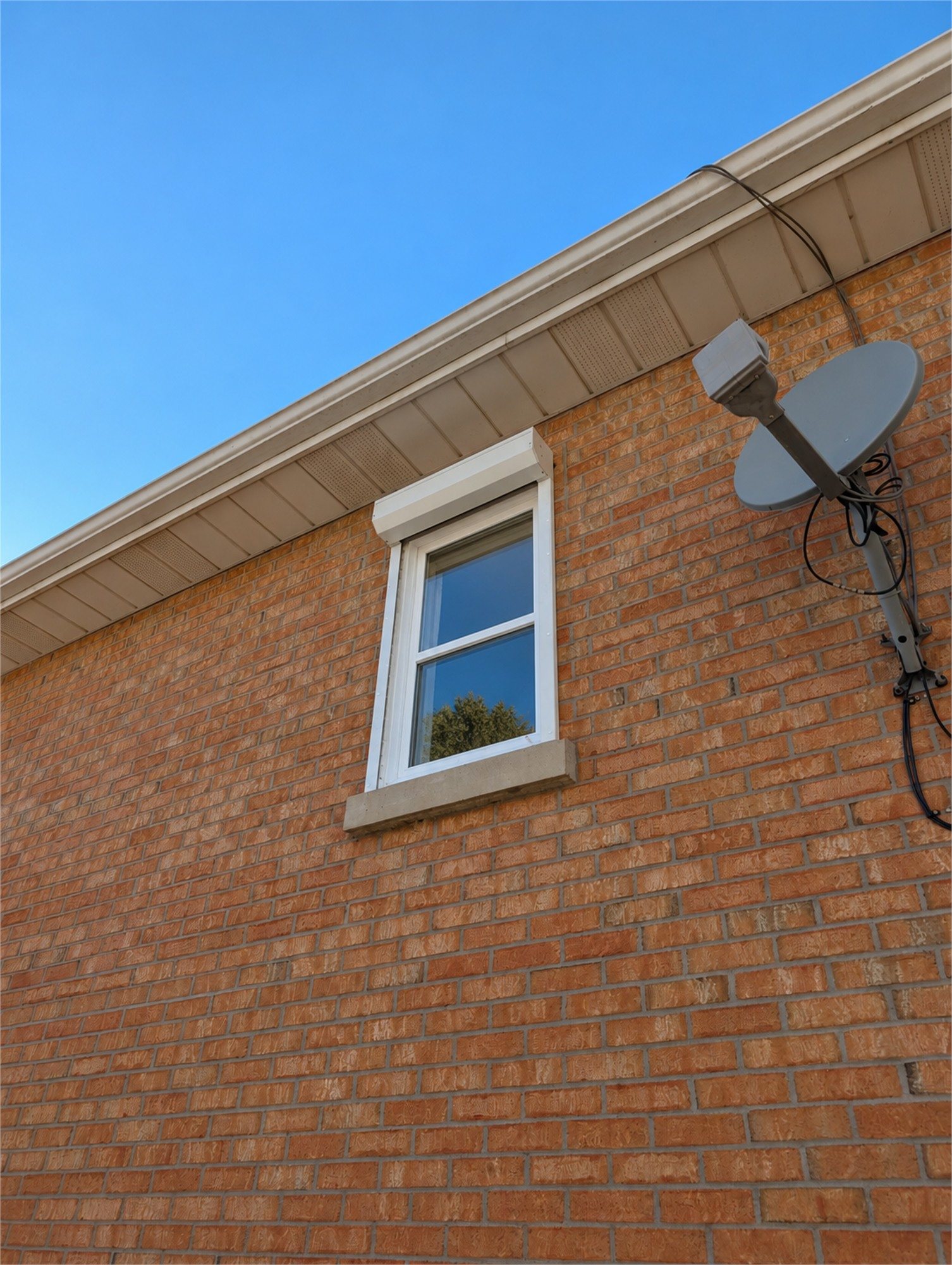 Illustration of a white roll shutter raised into its housing above a window on a brick house