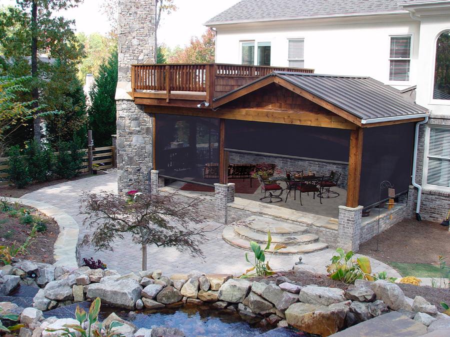 Retractable screens lowered across the openings of a covered stone and timber patio