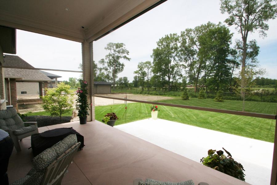 View of a lawn through a retractable screen on a covered patio