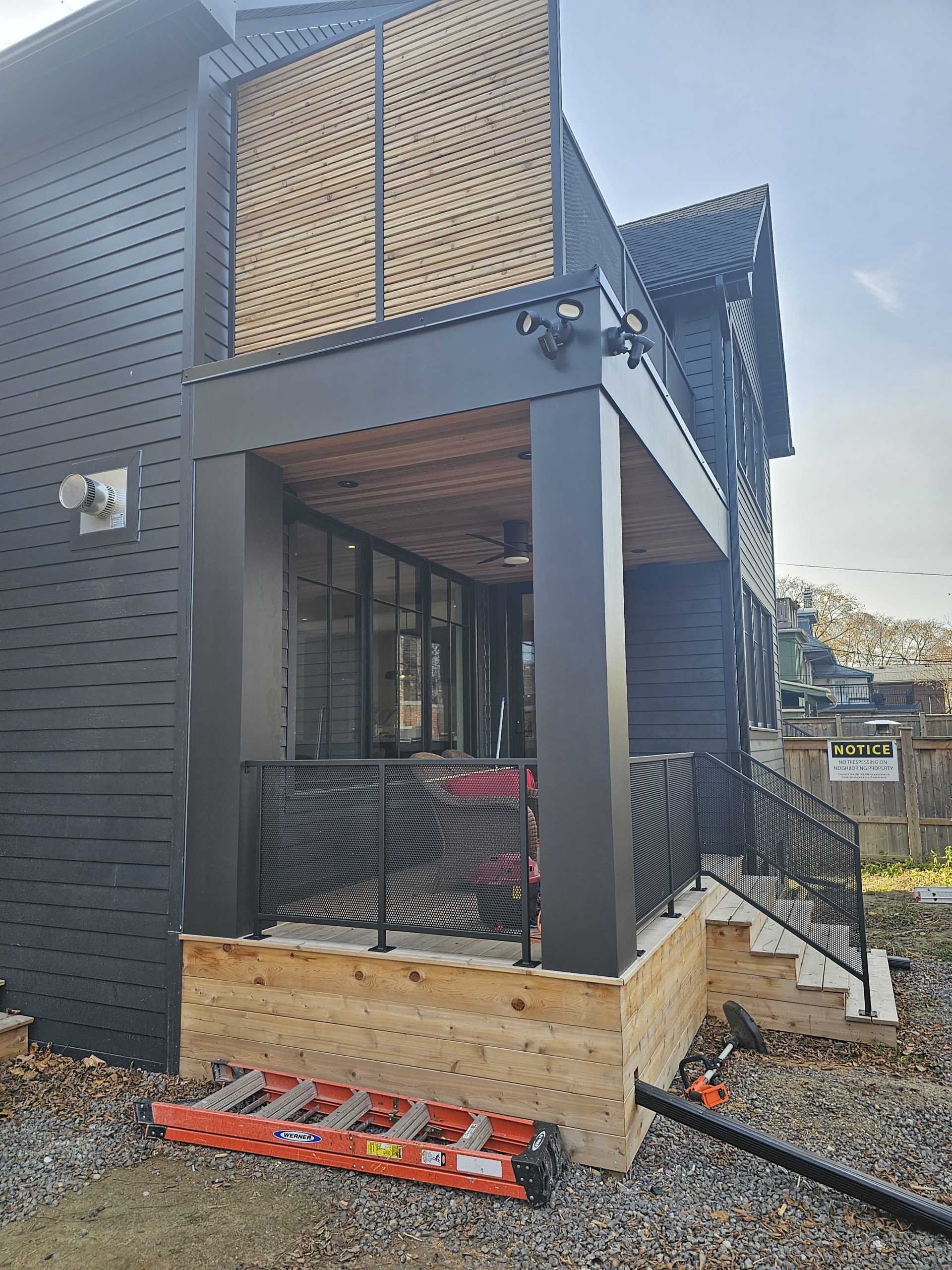 Rigid metal privacy screen with framed panel sections beside an exterior stair and deck area