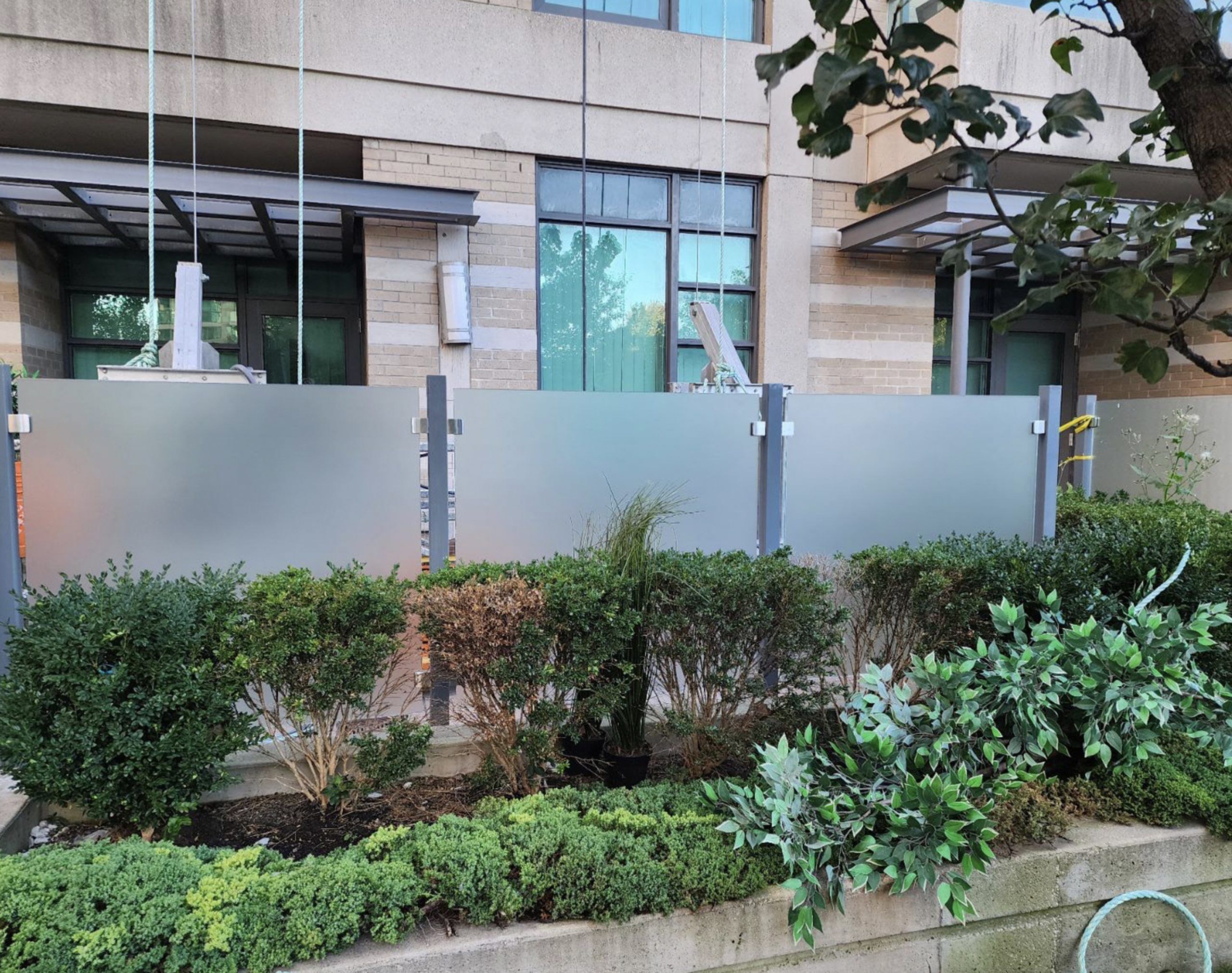 Metal-framed frosted privacy screens creating permanent outdoor separation