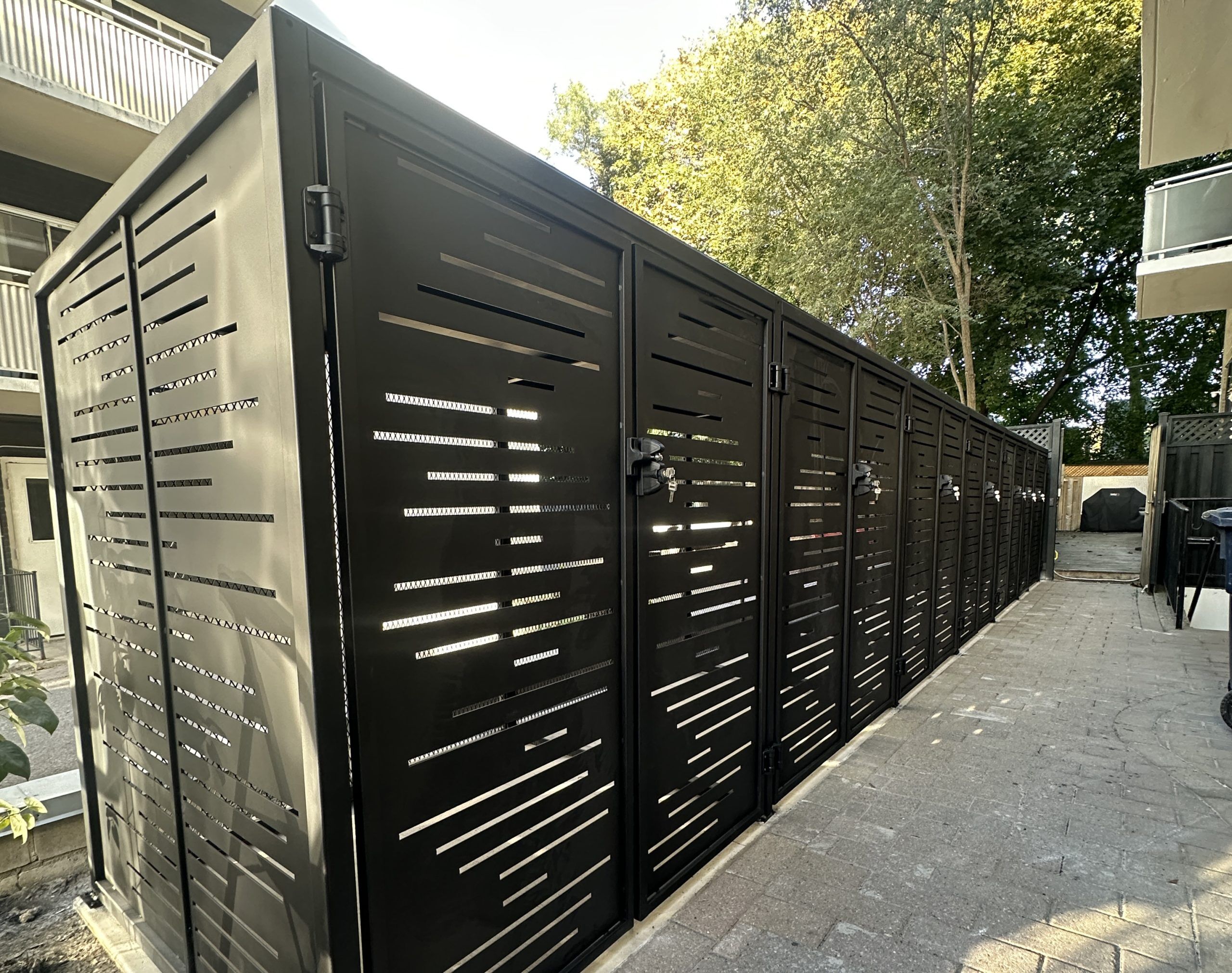 Long row of lockable black metal equipment enclosures with screened panels