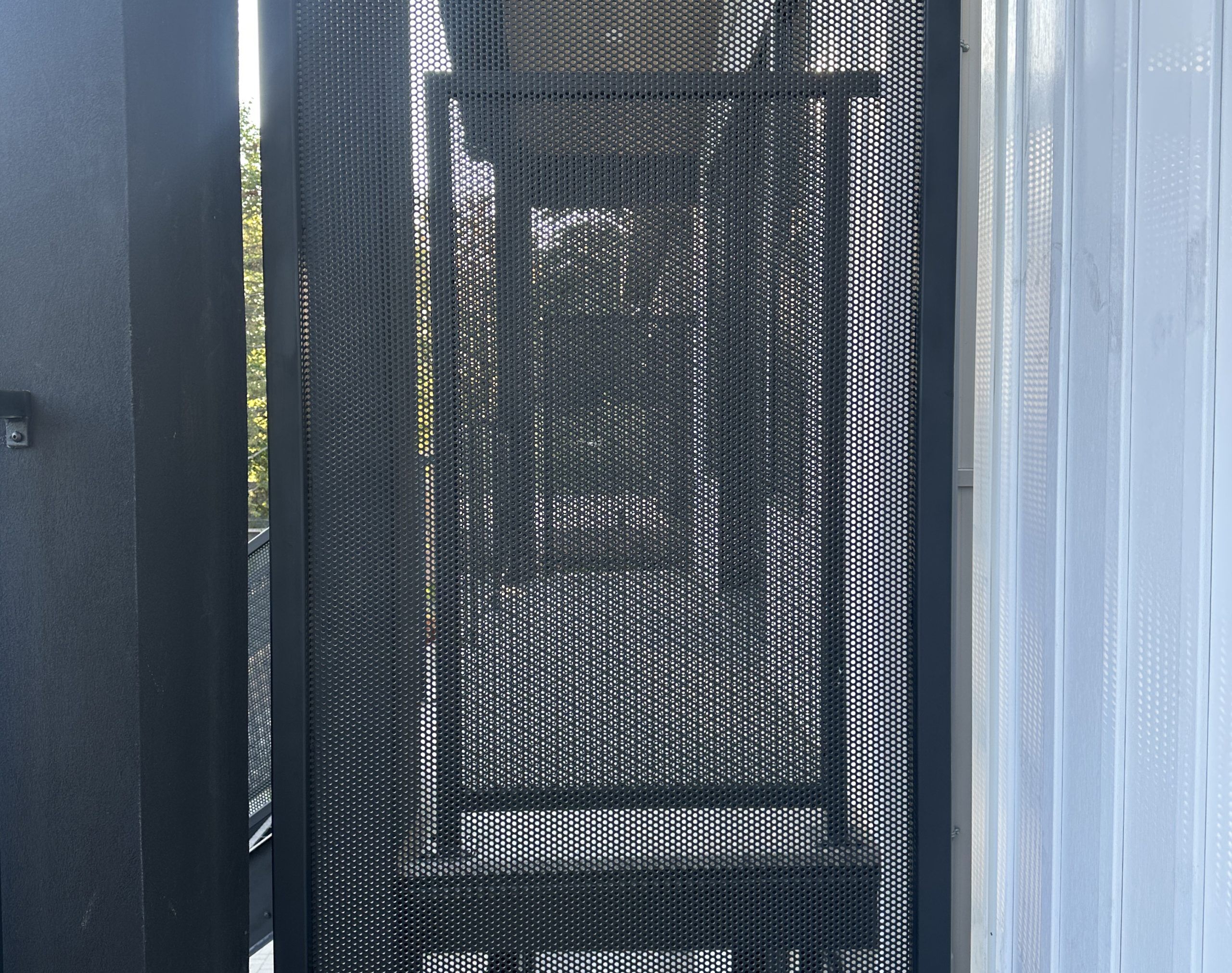 Perforated metal equipment enclosure protecting outdoor mechanical assets