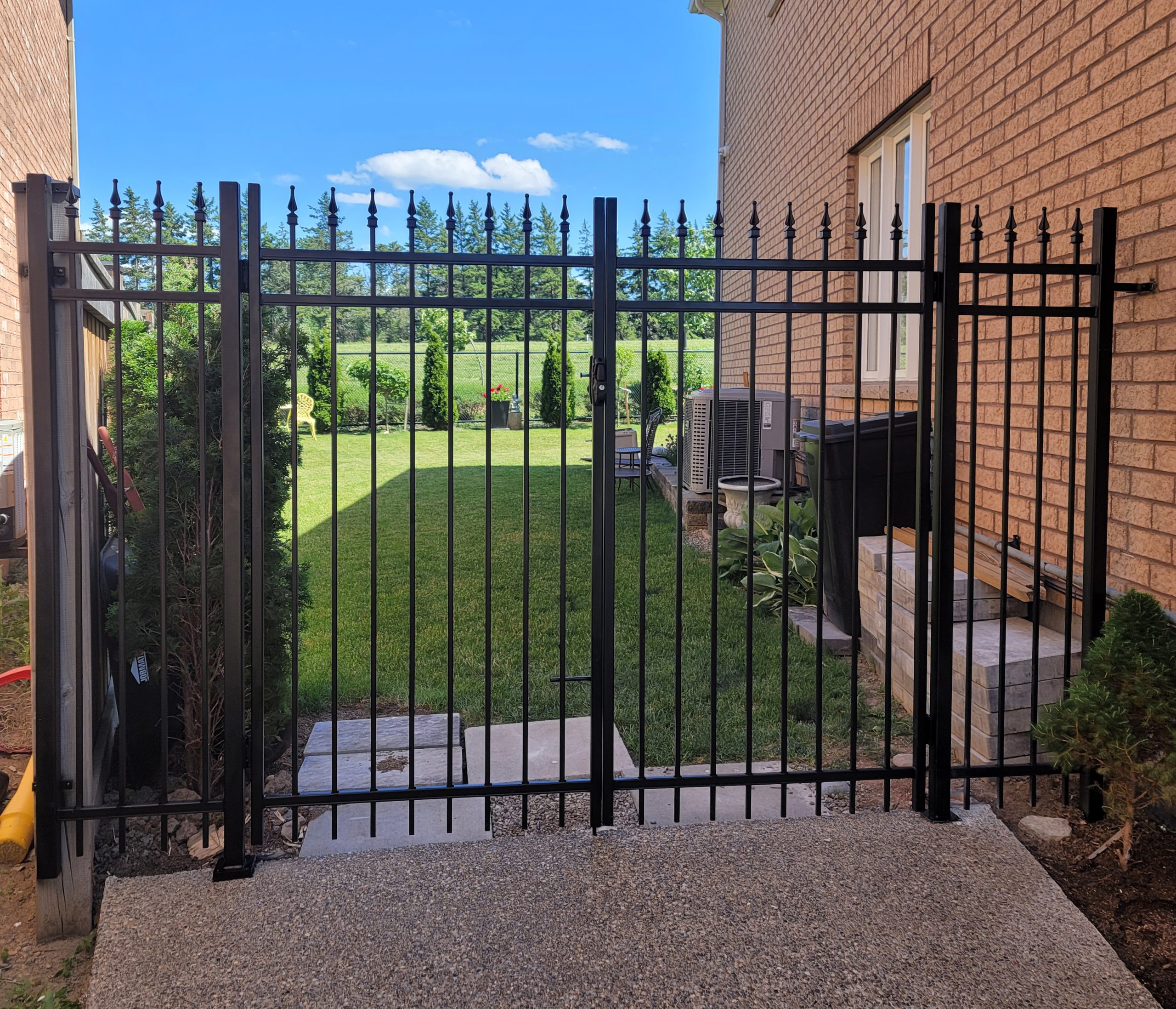 Black metal fence with spear-top pickets protecting a side-yard boundary