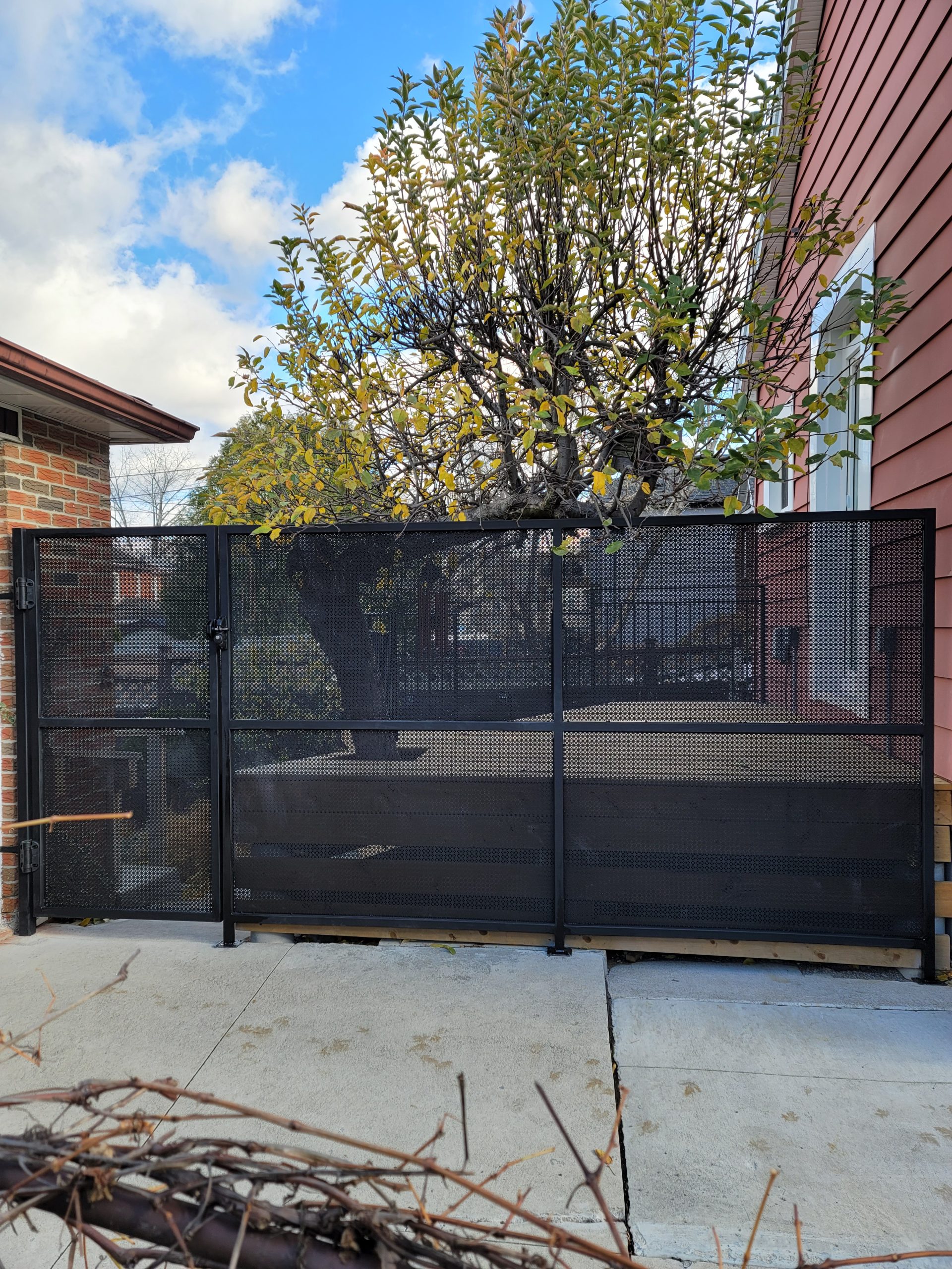 Black perforated metal security gate across a residential driveway