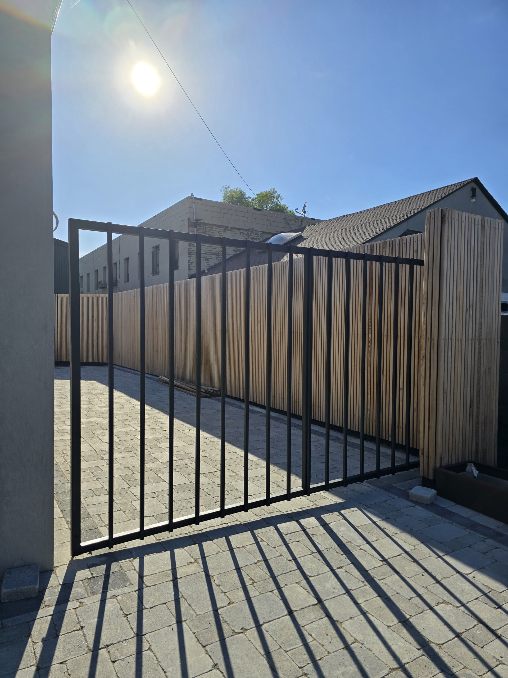 Black metal swing gate installed at a paved private access point