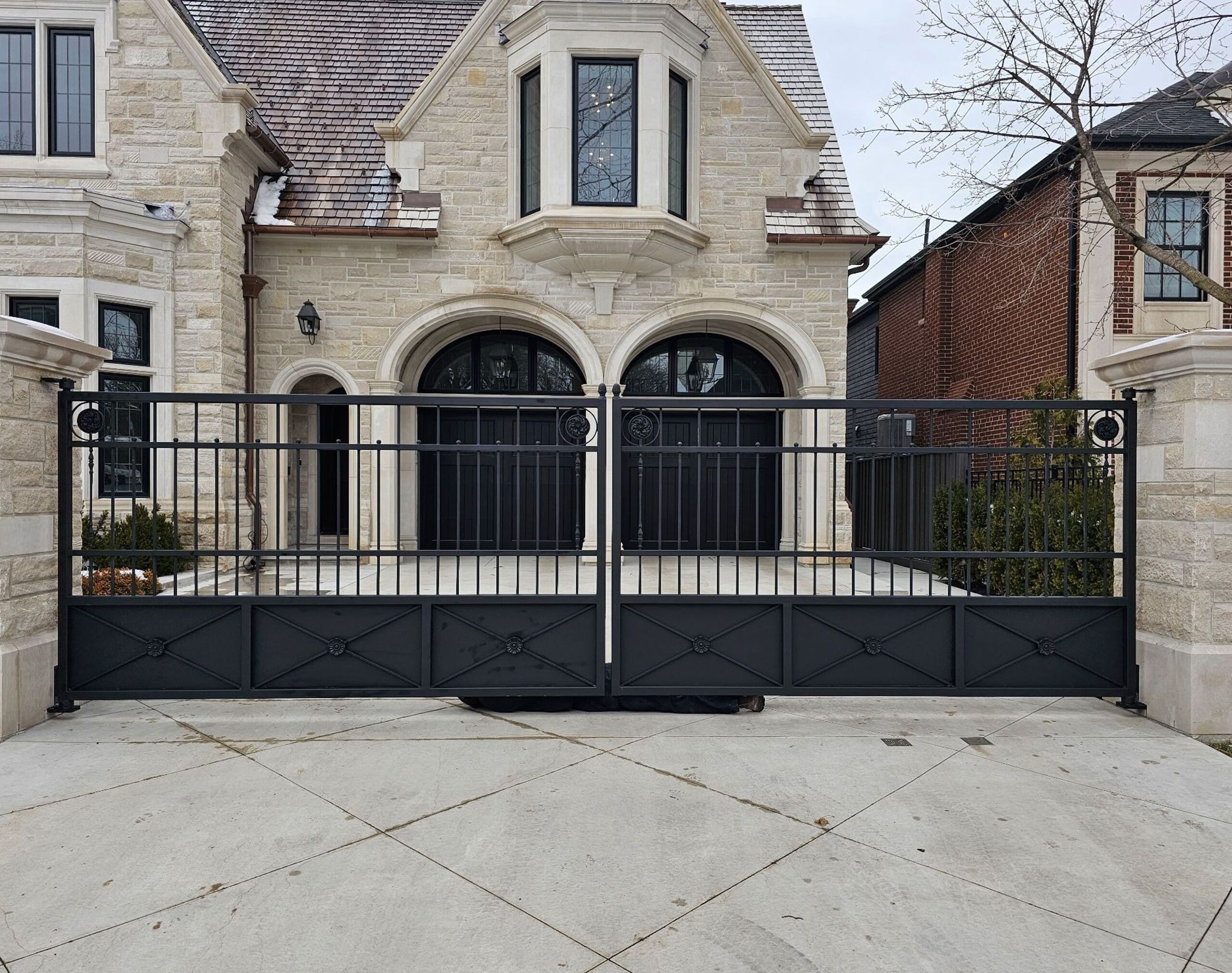 Black metal driveway security gate in front of a residential property