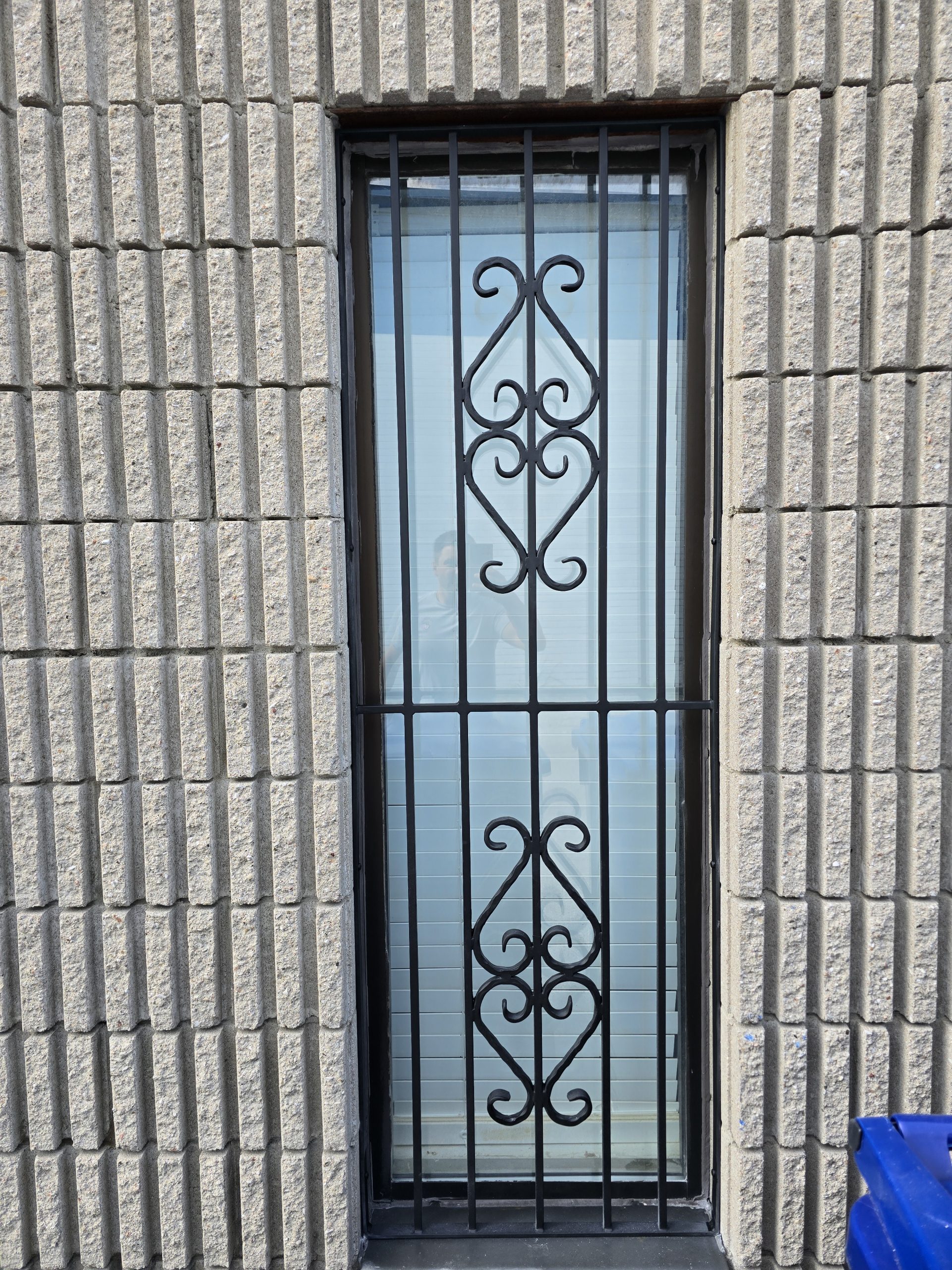 Custom black metal security grille mounted over a tall window opening