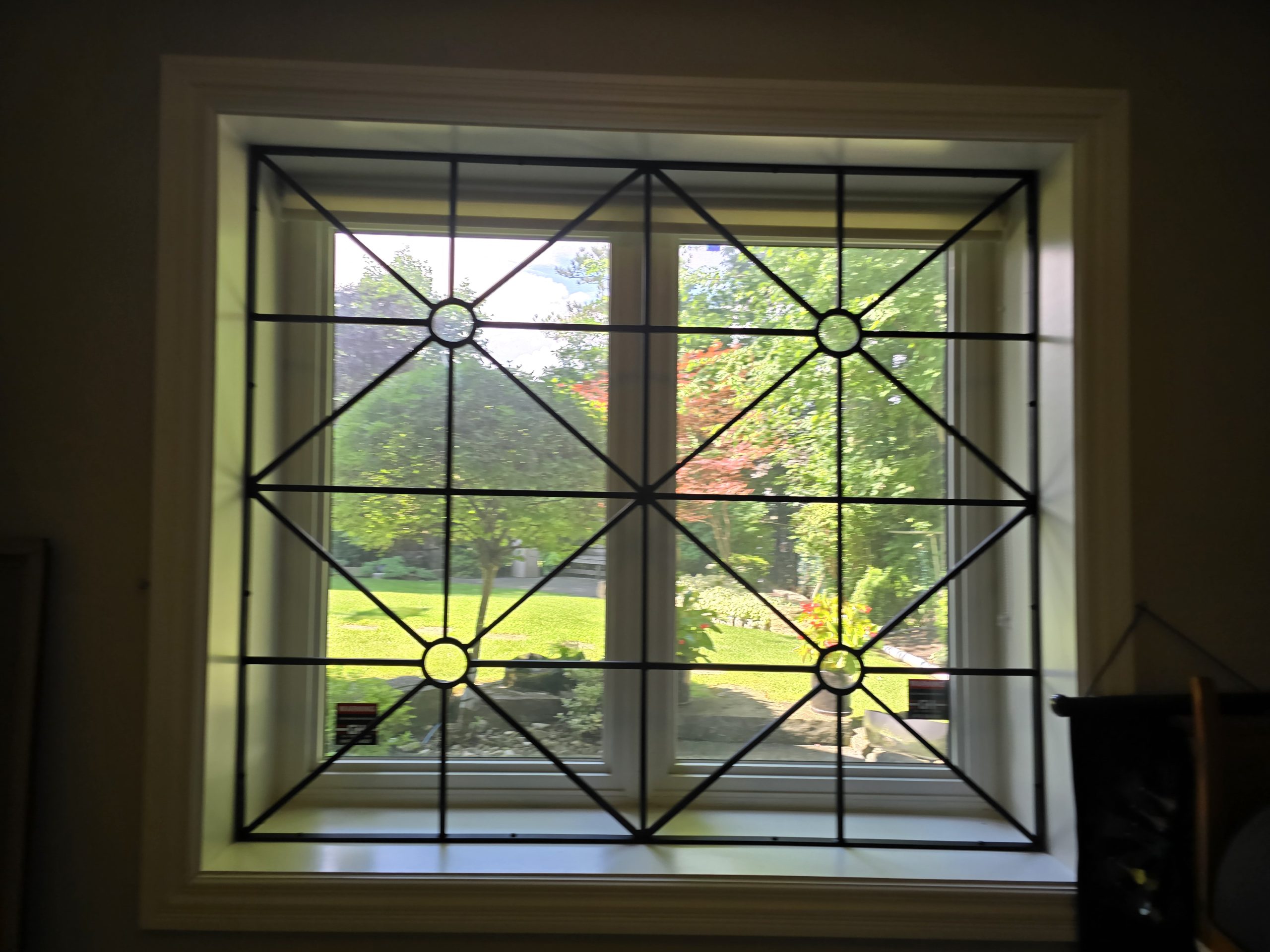 Black metal security grille protecting a residential window opening